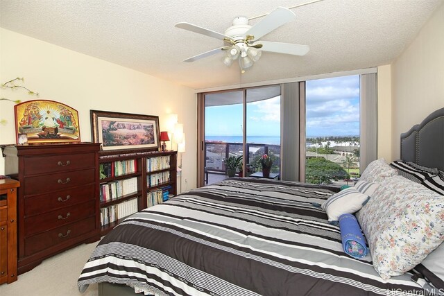 bedroom featuring access to exterior, a textured ceiling, light colored carpet, and ceiling fan