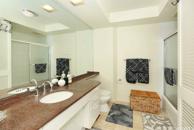 full bathroom with toilet, a tray ceiling, tile patterned floors, and bath / shower combo with glass door