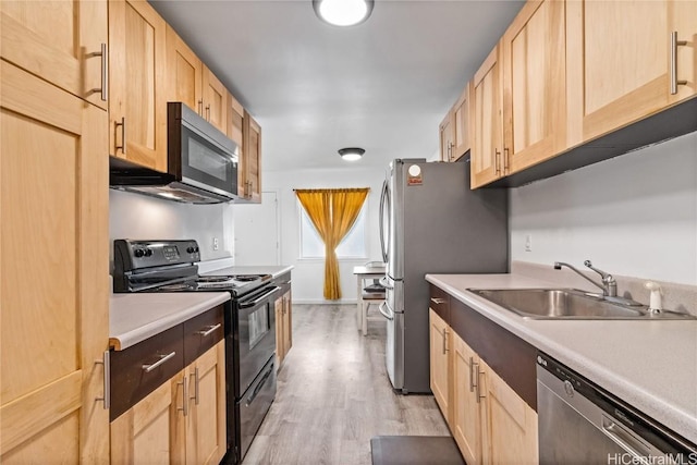 kitchen with appliances with stainless steel finishes, light brown cabinets, light hardwood / wood-style flooring, and sink