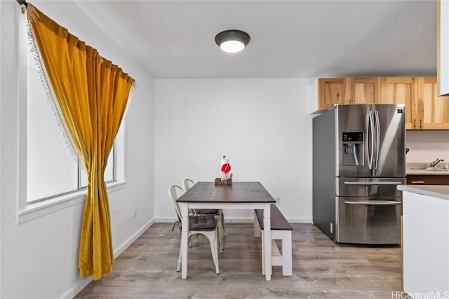 kitchen featuring light wood-type flooring, stainless steel fridge with ice dispenser, sink, and light brown cabinetry