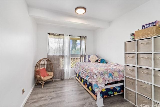 bedroom with beamed ceiling and hardwood / wood-style flooring