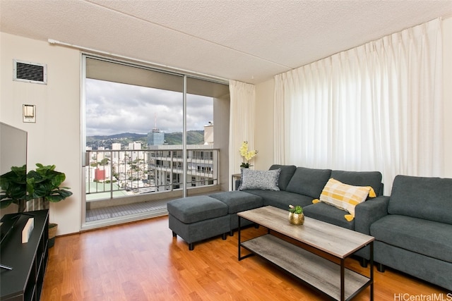 living room with wood-type flooring, a textured ceiling, and a wall of windows