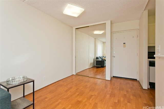 empty room with light hardwood / wood-style floors and a textured ceiling