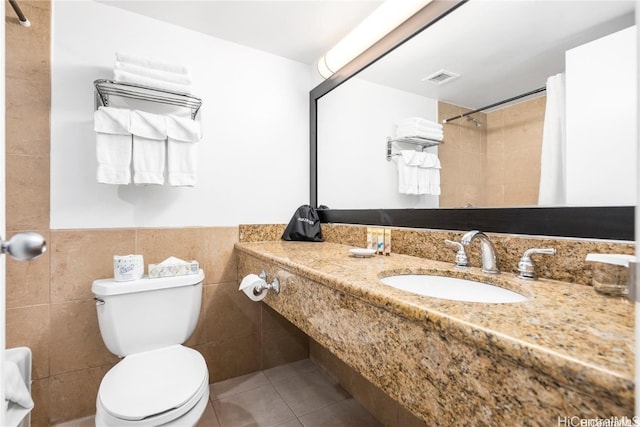 bathroom with toilet, tile walls, sink, and tile patterned floors