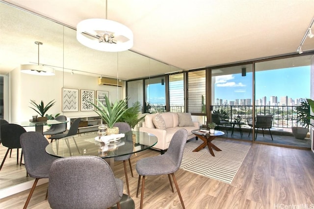 dining area with an AC wall unit, hardwood / wood-style floors, and a wall of windows