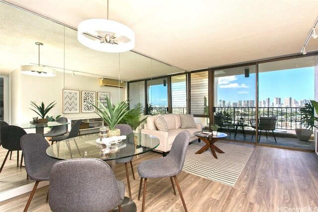 dining area featuring hardwood / wood-style flooring, expansive windows, a wall mounted AC, and track lighting