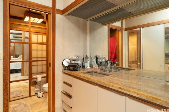 bar featuring light stone countertops, white cabinetry, and sink