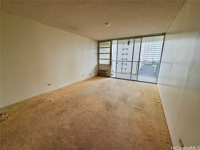 carpeted spare room featuring a wall mounted AC and a textured ceiling