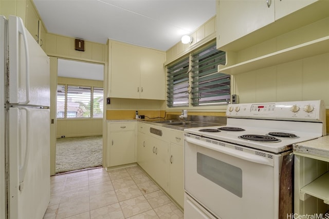 kitchen featuring light carpet, cream cabinets, and white appliances