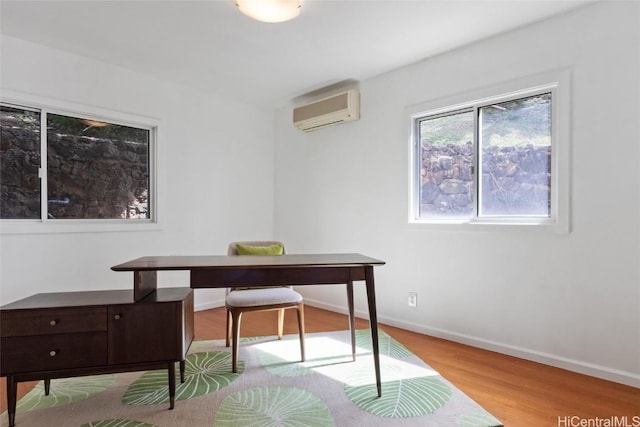 office area with light wood-type flooring and an AC wall unit