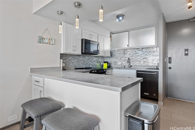 kitchen with kitchen peninsula, white cabinetry, a kitchen bar, and appliances with stainless steel finishes