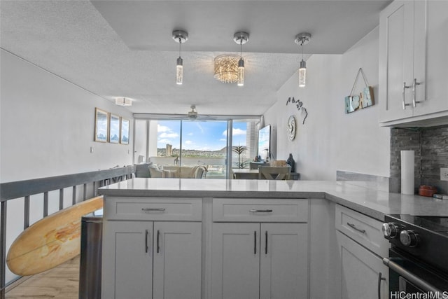 kitchen with kitchen peninsula, a textured ceiling, light hardwood / wood-style flooring, and white cabinetry