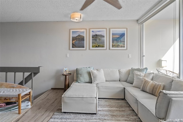 living room featuring wood-type flooring, a textured ceiling, and ceiling fan