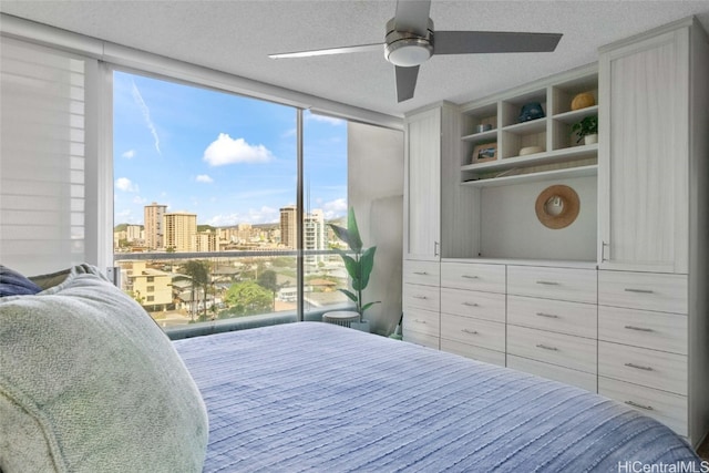 bedroom with ceiling fan, a textured ceiling, and a wall of windows