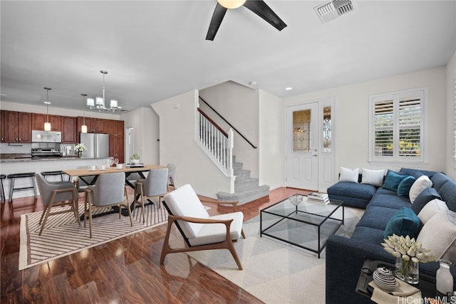 living room featuring ceiling fan with notable chandelier and light hardwood / wood-style flooring