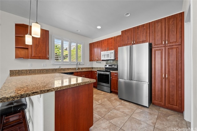 kitchen featuring stone counters, hanging light fixtures, kitchen peninsula, a kitchen bar, and appliances with stainless steel finishes