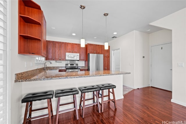 kitchen featuring hanging light fixtures, dark hardwood / wood-style floors, light stone counters, kitchen peninsula, and stainless steel appliances