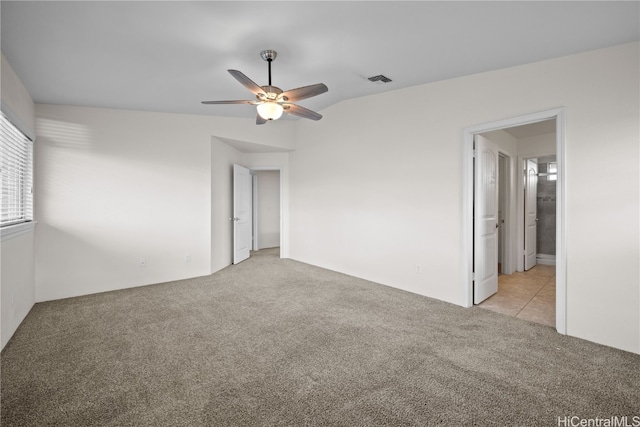 unfurnished bedroom featuring light colored carpet, ensuite bath, and ceiling fan