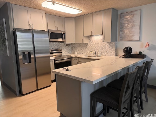 kitchen featuring gray cabinets, appliances with stainless steel finishes, kitchen peninsula, and sink