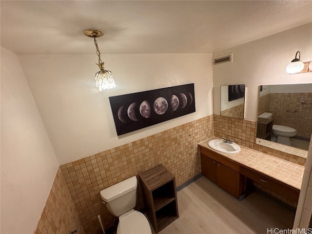 bathroom featuring toilet, vanity, tile walls, and wood-type flooring