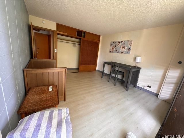 bedroom with a closet, a textured ceiling, and light hardwood / wood-style flooring