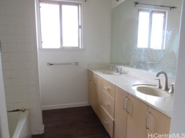 bathroom with vanity, hardwood / wood-style flooring, a bathtub, and a healthy amount of sunlight