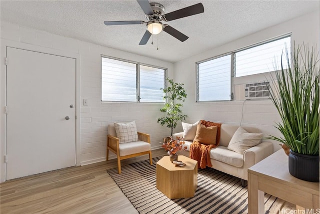 living room with a textured ceiling, light hardwood / wood-style floors, ceiling fan, and cooling unit