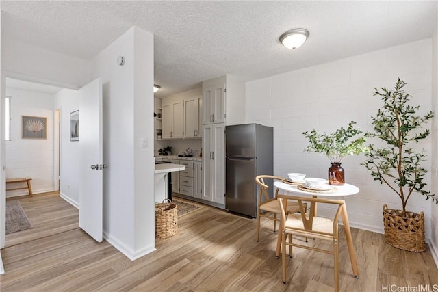 kitchen with gray cabinetry, stainless steel fridge, light hardwood / wood-style floors, and a textured ceiling