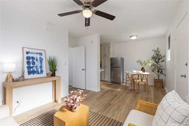 living room with ceiling fan, a textured ceiling, and hardwood / wood-style flooring