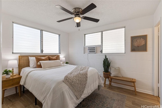 bedroom featuring a textured ceiling, hardwood / wood-style flooring, ceiling fan, and cooling unit