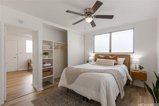 bedroom featuring hardwood / wood-style floors, a textured ceiling, and ceiling fan