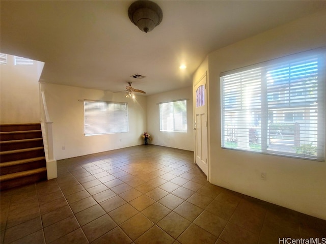 unfurnished living room with ceiling fan and dark tile patterned floors