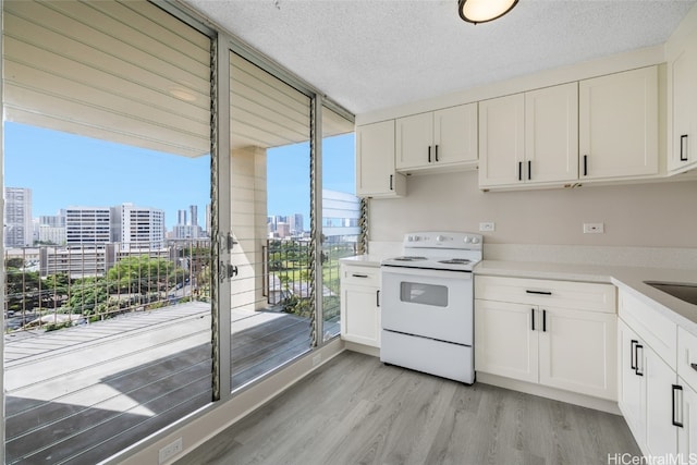 kitchen featuring white cabinets, a textured ceiling, light hardwood / wood-style flooring, and electric stove