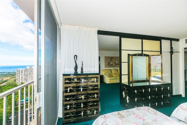 carpeted bedroom with multiple windows, a water view, and a textured ceiling