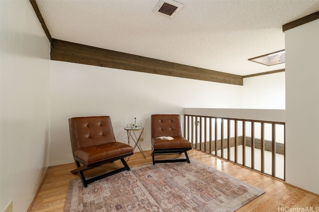 sitting room featuring wood-type flooring, a textured ceiling, and a skylight