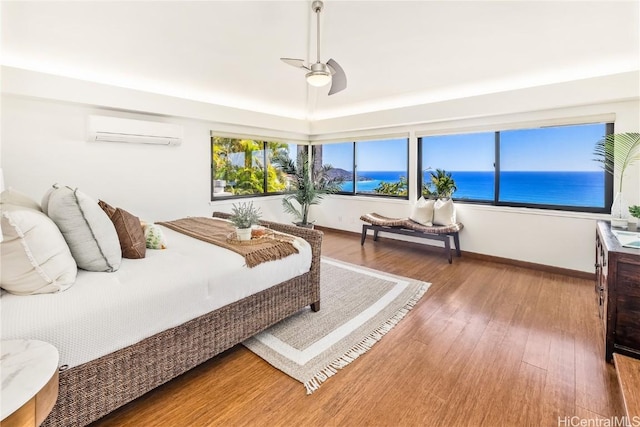 bedroom featuring ceiling fan, a water view, wood-type flooring, and a wall mounted air conditioner