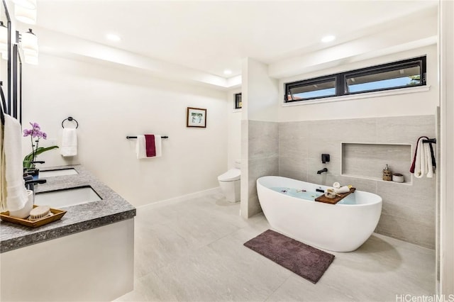 bathroom featuring tile patterned floors, a bathtub, toilet, and tile walls