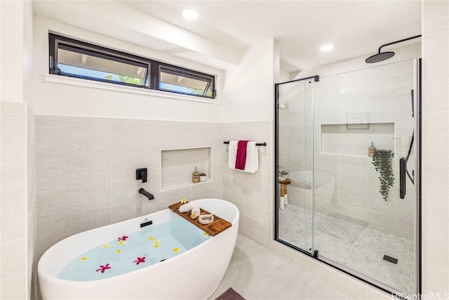 bathroom featuring independent shower and bath and tile walls