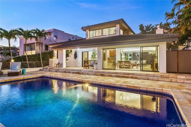 pool at dusk with a patio area