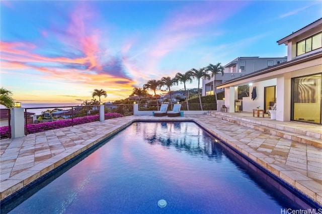 pool at dusk featuring a patio area