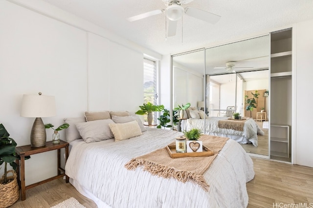 bedroom featuring a closet, ceiling fan, light hardwood / wood-style flooring, and a textured ceiling