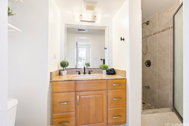 bathroom featuring a tile shower, vanity, and toilet