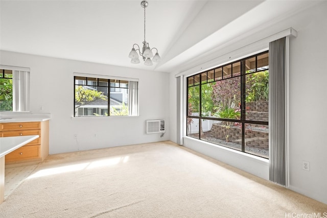 carpeted spare room with a chandelier, vaulted ceiling, and a wealth of natural light