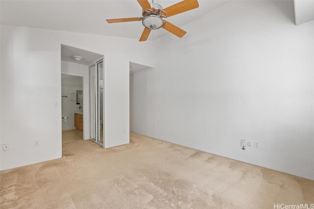 spare room featuring light colored carpet, vaulted ceiling, and ceiling fan