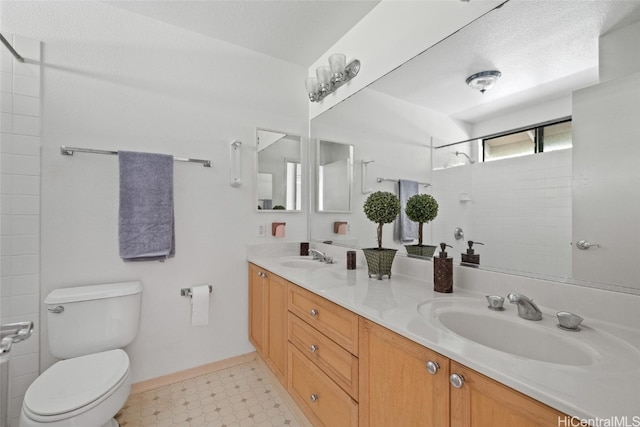 bathroom with a tile shower, vanity, a textured ceiling, and toilet