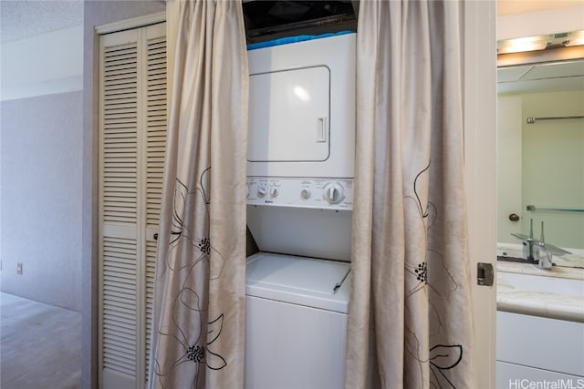 laundry room with a textured ceiling and stacked washer and clothes dryer