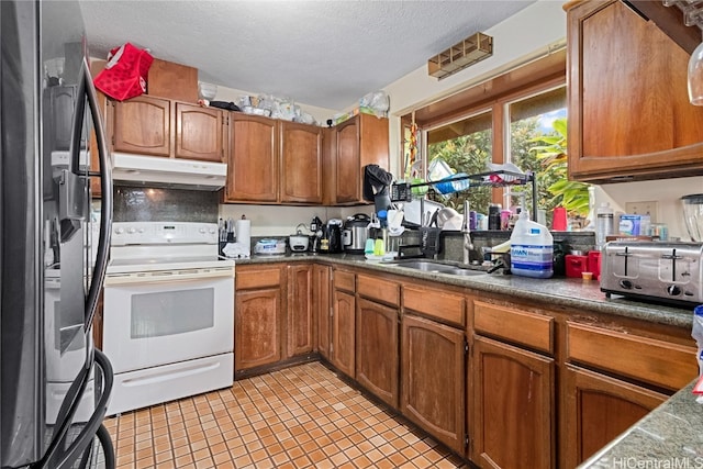 kitchen featuring stainless steel fridge, a textured ceiling, white range with electric stovetop, sink, and light tile patterned flooring