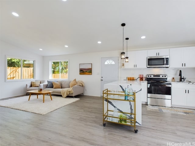 kitchen featuring pendant lighting, white cabinetry, appliances with stainless steel finishes, and light hardwood / wood-style flooring