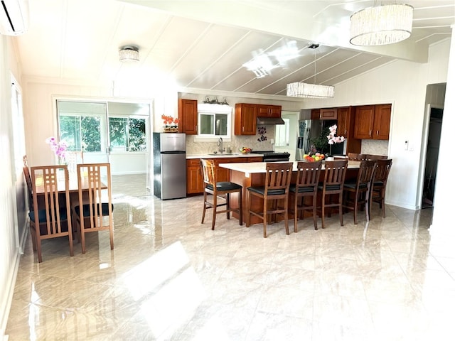 kitchen with sink, a wall mounted AC, stainless steel fridge, a breakfast bar, and a kitchen island