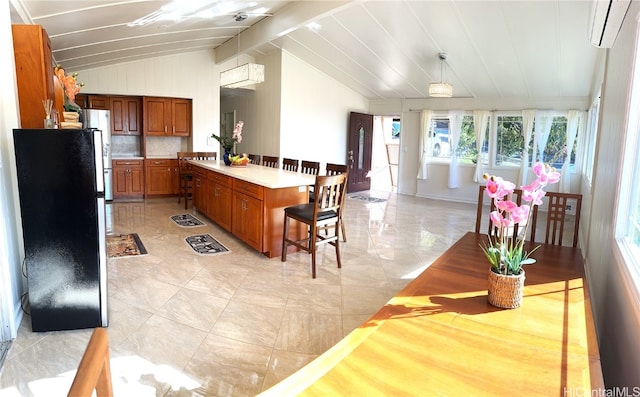 kitchen with a breakfast bar, a wall unit AC, white refrigerator, hanging light fixtures, and lofted ceiling